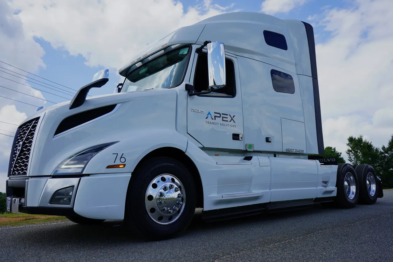 A white Apex Transit Volvo tractor, number 76, seen from a low angle against a blue sky.